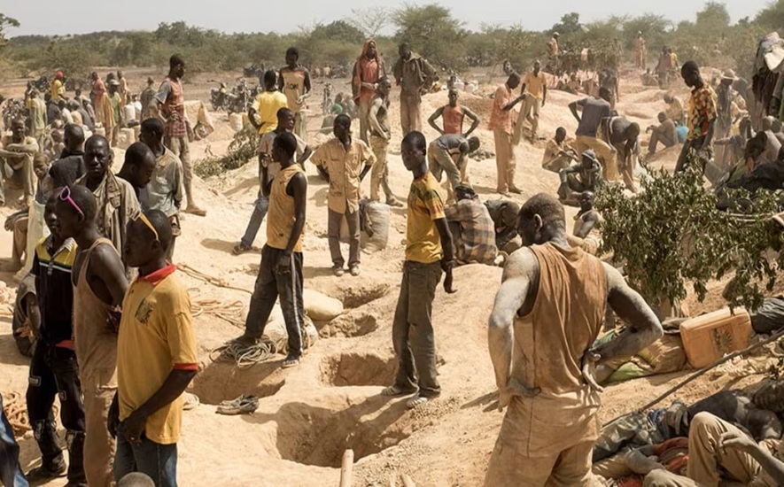 Artisanal gold miners panning for gold in an open pit in Mandiana, Guinea, illustrating the hazardous outdoor conditions wher